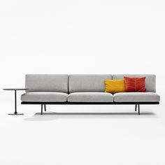 a gray couch with two orange and yellow pillows on it's backrests