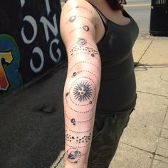 a woman is standing on the sidewalk with her arm covered in solar and moon tattoos