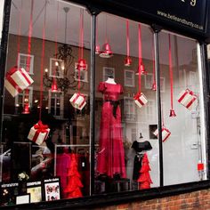 a storefront window with red and white items in the display windows, hanging from strings