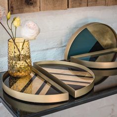 a glass vase with flowers in it sitting on a table next to plates and mirrors