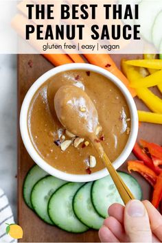 the best thai peanut sauce in a white bowl with cucumbers and carrots