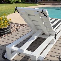 a white lawn chair sitting on top of a wooden deck next to a swimming pool