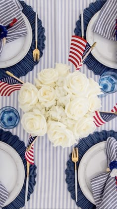 the table is set with white roses and red, white, and blue napkins