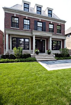 a large brick house sitting on top of a lush green field