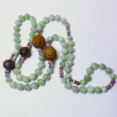 On offer is this elegant Vintage Chinese Necklace featuring large 10 mm Translucent Green Jadeite beads with 14 karat Yellow Gold Corrugated Spacer Beads between genuine Amethyst beads with two spectacular 20mm diameter Hand Carved Shou and Bat Design Wooden beads and two 14 mm diameter Hand Carved Shou Wooden beads that are lower down on the necklace. Measuring a nice opera length of 36 inches with no clasp as it slips over your head. The translucent Jadeite and Amethyst are genuine gemstones w Green Mala With 8mm Beads For Healing, Green Gemstone Beads Mala For Healing, Spiritual Jade Jewelry With 108 Beads, Jade Gemstone Beaded Necklaces With Round Beads, Jade Gemstone Beaded Necklace With Round Beads, Green Hand-strung Mala With Round Beads, Green Hand-strung Mala, Jade 8mm Beads For Jewelry Making, Green Gemstone Beads Mala