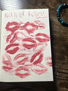 a book with lipstick drawn on it next to a beaded bracelet and necklace that says, wall of kisses