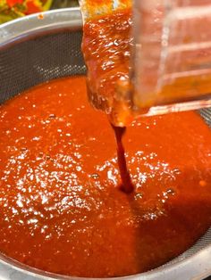 someone pouring sauce into a metal bowl