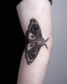 a black and white butterfly tattoo on the arm