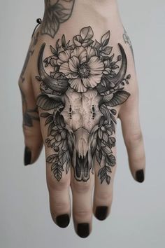 a woman's hand with flowers and a skull on the middle of her palm