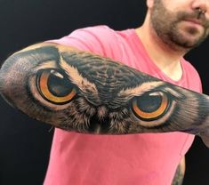 an owl tattoo on the arm with yellow eyes and black wings is shown in front of a man's face