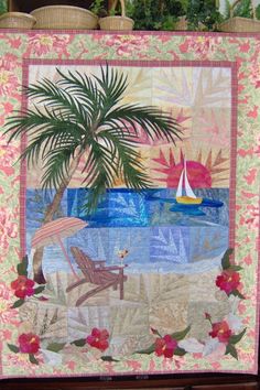 a quilted wall hanging with a palm tree, beach chair and sailboat on the water