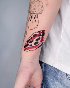 a ladybug and mushroom tattoo on the left arm, with stars in the background