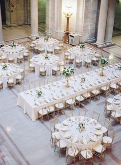 tables and chairs are set up in the middle of a room with columns, pillars, and chandeliers