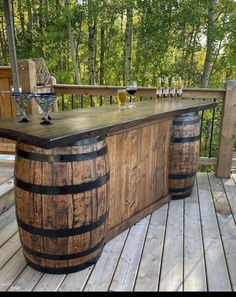 an outdoor bar made out of wooden barrels on a deck with wine glasses sitting on it