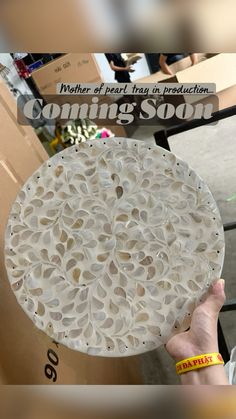 a person holding up a white plate with holes in it and the words coming soon written on it