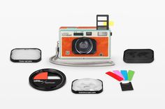 an orange and white polaroid camera sitting on top of a table next to other items