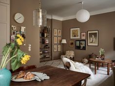 a living room filled with lots of furniture and pictures on the wall next to a table