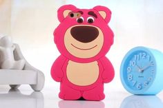 a pink bear phone case next to a blue clock