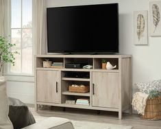 a flat screen tv sitting on top of a wooden entertainment center in a living room