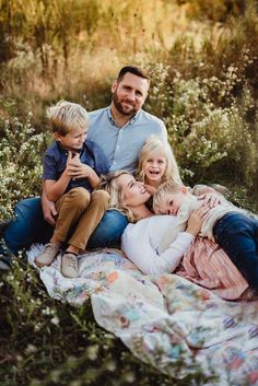 a family sitting on a blanket in the middle of a field