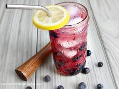 a drink with blueberries and lemon on the side