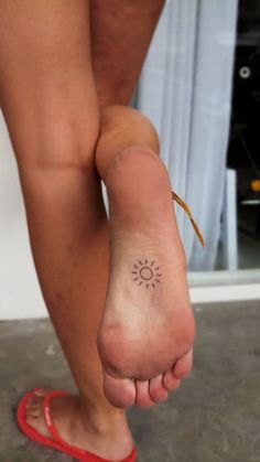 a woman's foot with a small sun tattoo on her left leg and the word,