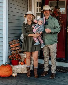 a man and woman are standing on the porch with their baby in front of them