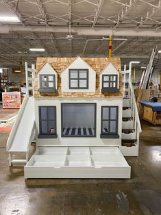 a fake house made out of cardboard with windows and doors on the roof, sitting in a warehouse