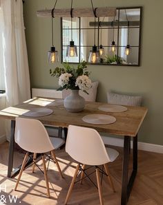 a dining room table with four chairs and a vase filled with flowers on top of it