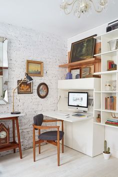 a desk with a computer on top of it in front of a white brick wall