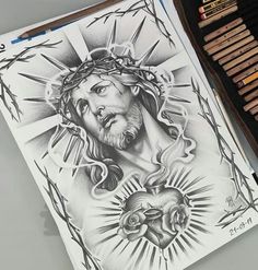 a pencil drawing of jesus on paper next to some crucifixs and colored pencils