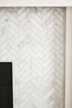 a white marble herringbone tile backsplash with a black door in the center