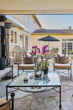 a living room filled with furniture next to a large patio covered in flowers and an umbrella