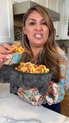 a woman is holding a bowl of food in her hands and looking at the camera