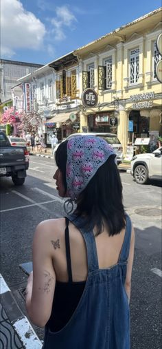 a woman in overalls and a knitted hat is looking at the street corner