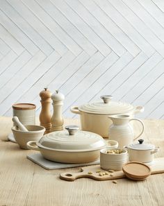 a table topped with pots and pans on top of a wooden table next to utensils