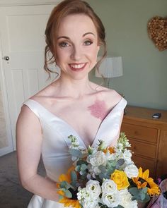 a woman in a wedding dress holding a bouquet with sunflowers and roses on it