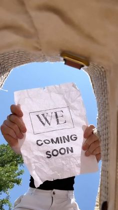 a person holding up a paper sign that says we are coming soon