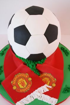 a soccer ball on top of a cake with the flag of portugal and manchester's crest