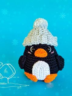 a crocheted penguin with a hat on it's head sitting next to a snowflake