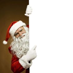 a man dressed as santa claus peeking out from behind a white board with his thumb up