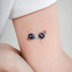 two small tattoos on the side of a woman's leg, one with blue eyes