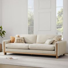 a living room with a white couch and potted plant on the floor next to it