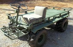 a green utility vehicle parked on top of a gravel field