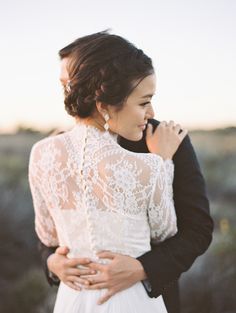 a man and woman standing next to each other in front of the sun with their arms around each other