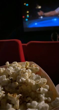 a bowl filled with popcorn sitting on top of a table next to a red chair