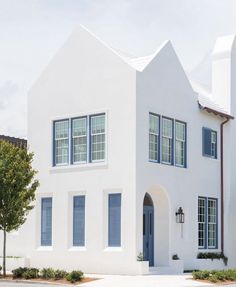 a large white house with blue shutters on the front and side windows is shown