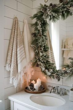 a christmas wreath is hung on the wall next to a sink with candles in it