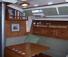 the inside of a boat with a wooden table and bookshelf on it's side