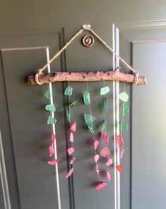 a wind chime hanging on the side of a door with sea glass and driftwood